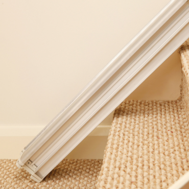 A stair lift track extends along carpeted stairs, providing accessibility in a home.