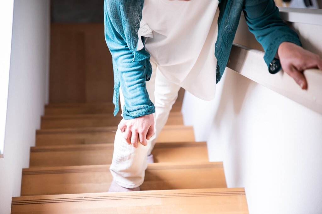 A woman holding her knee as she is on a staircase