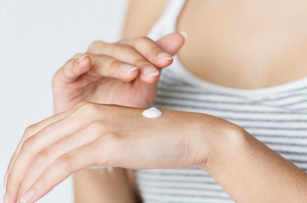 A woman rubbing cream into her hand