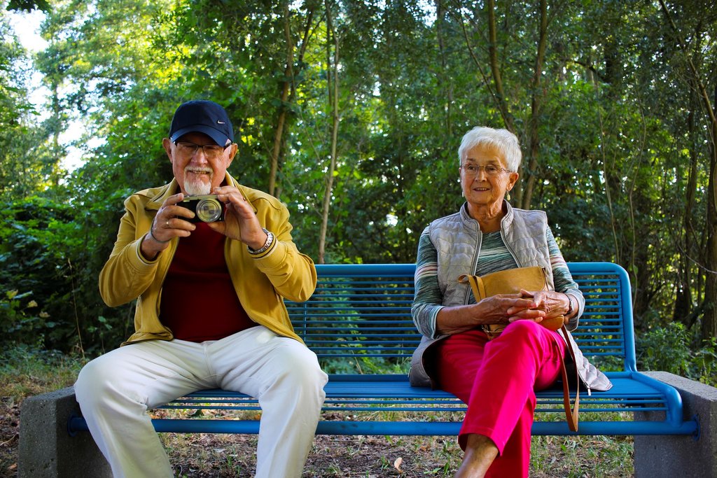 Older couple sat on bench taking a photograph