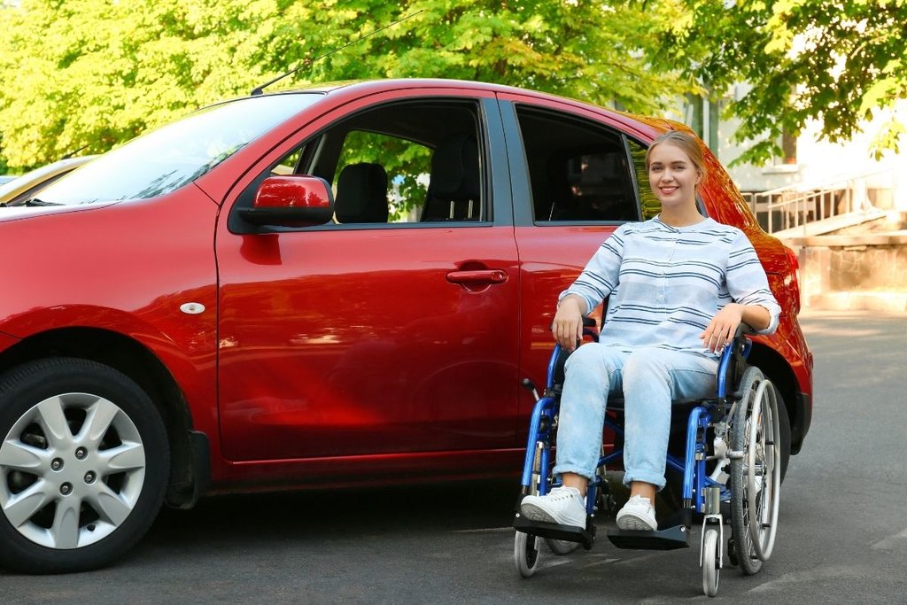 Lady in wheelchair outside red car