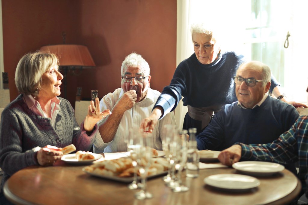 Older friends around a dinner table together