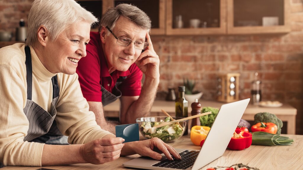 Older couple online shopping in the kitchen
