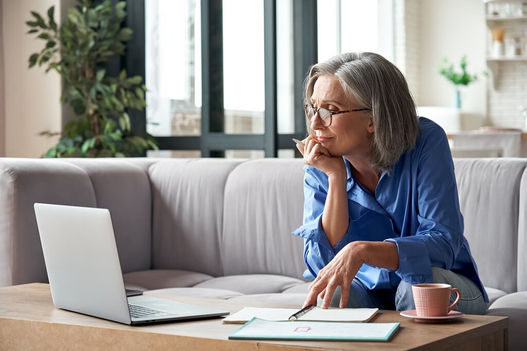 A woman with a laptop, a pen, and paper