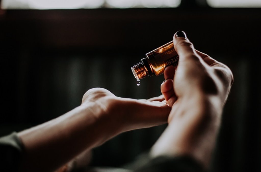 A woman tipping skincare product out of a bottle