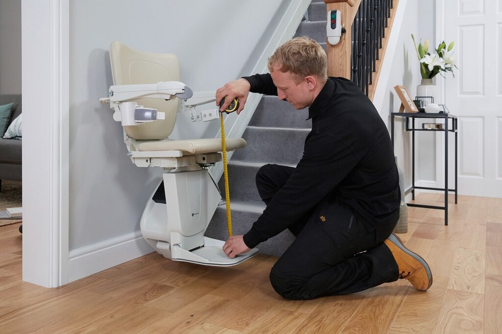 A stairlift engineer measuring a stairlift
