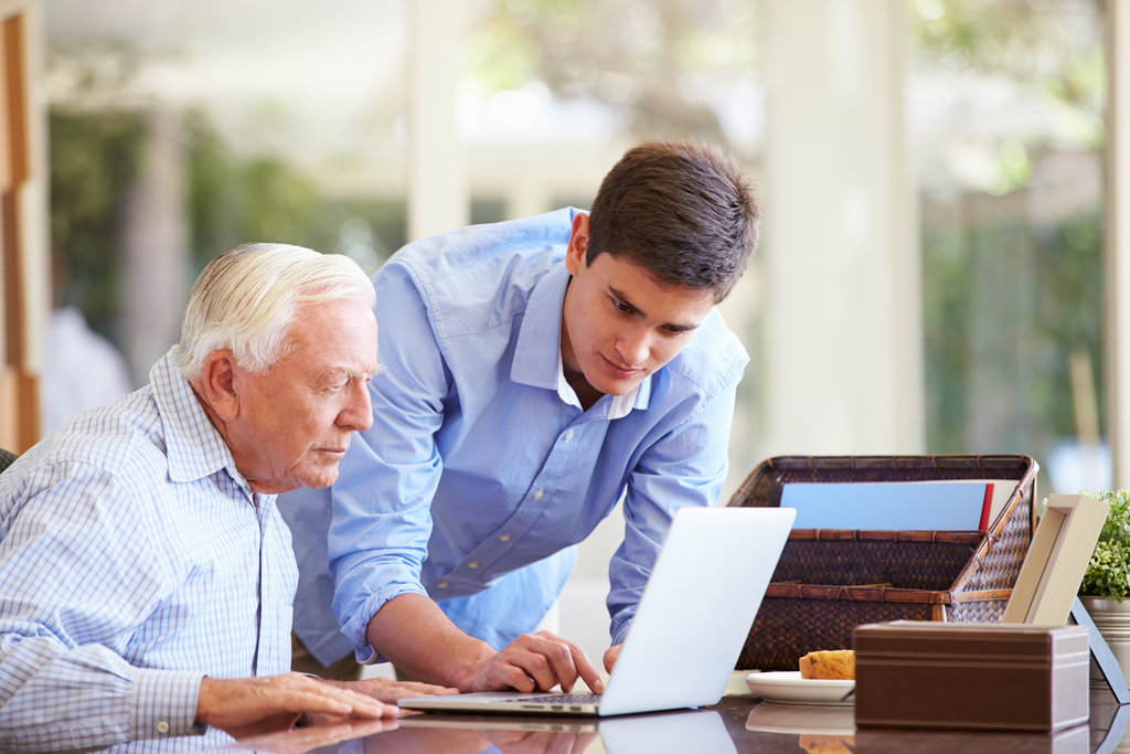 older man using a laptop with an assistant