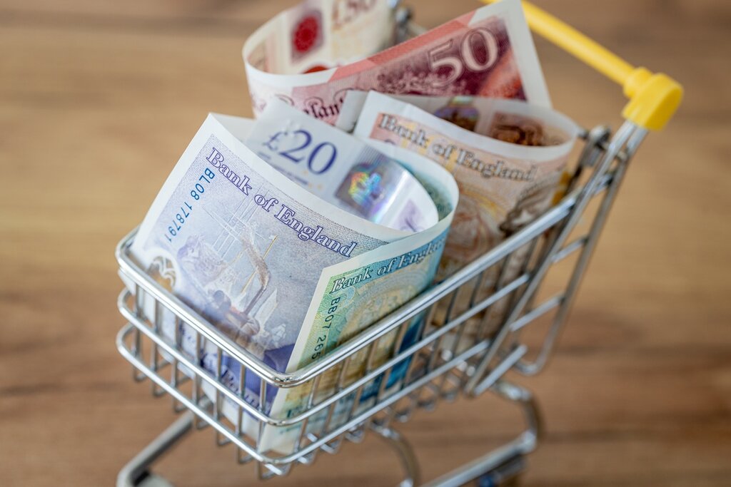 A miniature shopping trolley with British pounds in