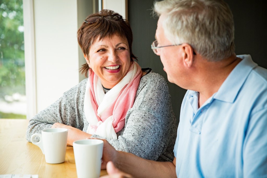 Two older people chatting over a drink