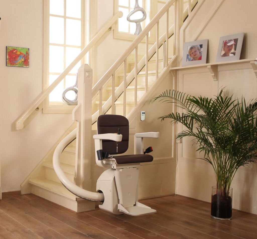 A stairlift at the bottom of a curved staircase