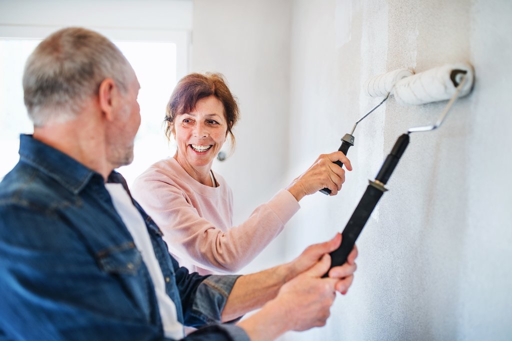 Senior couple painting walls together in house